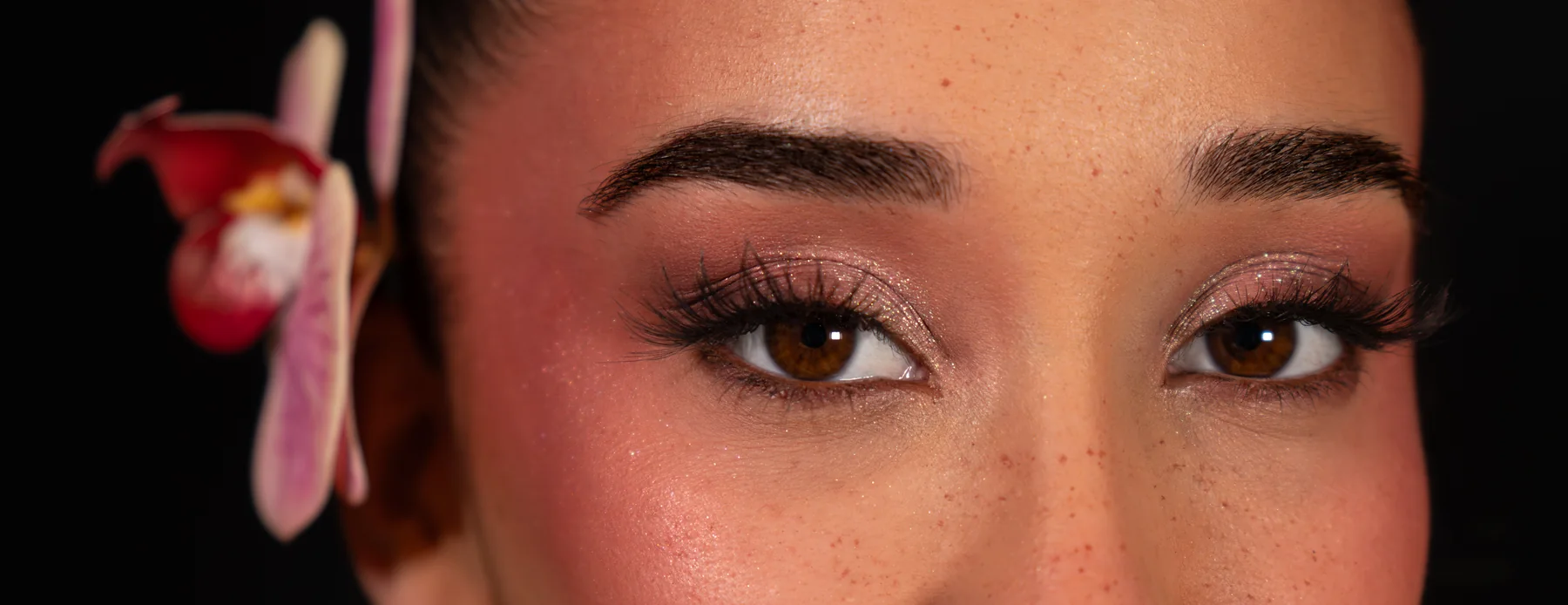 Plano detalle de la mirada con el maquillaje de ojos y la orquídea