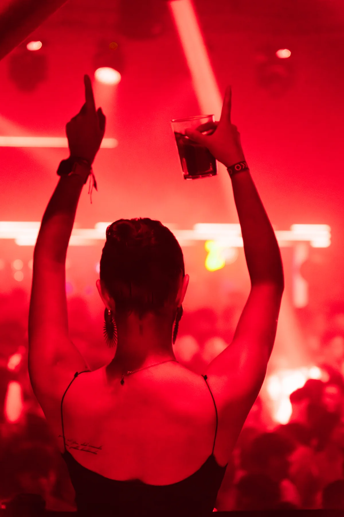 Una chica con los brazos en alto bajo luz roja